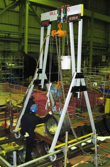 Two eme 6600 lb capacity aluminum gantry cranes deployed in a paired-lift configuration over a generator component at a nuclear power plant maintenance facility, with a worker positioning the load.